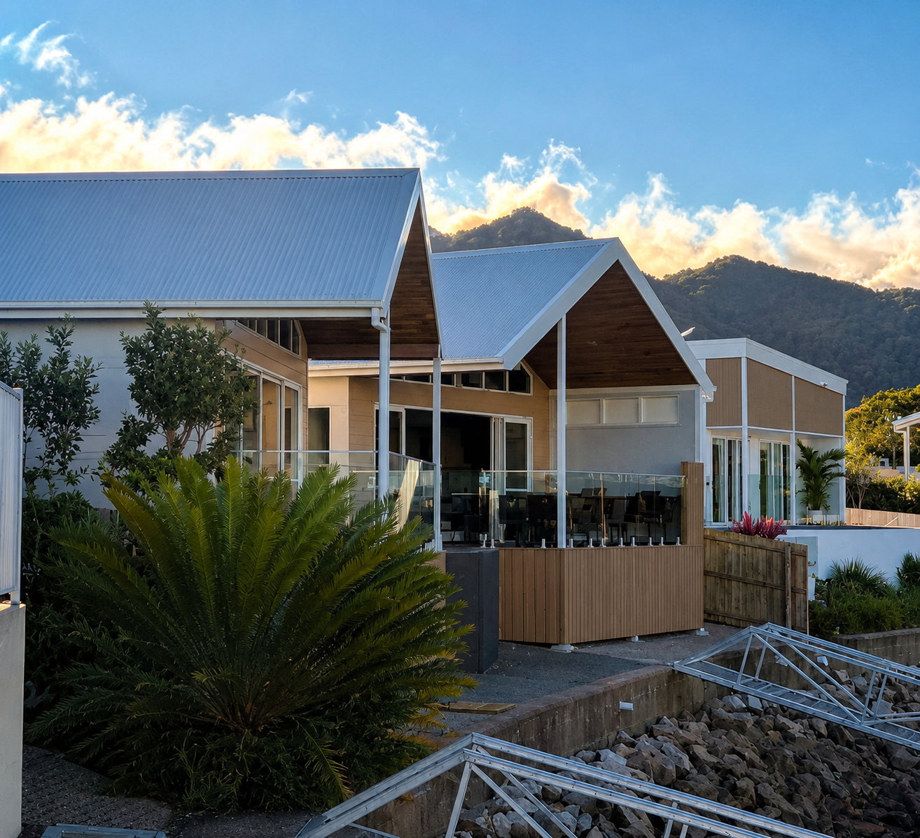 Marina completed build — timber gable pavilion with covered alfresco, glass balustrade and mountain backdrop at golden hour