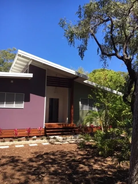 42 HL — completed exterior with purple and green cladding, timber deck and tropical garden