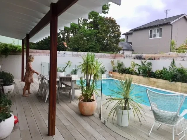 Beach House — covered outdoor dining deck with timber pergola, potted palms and pool beyond