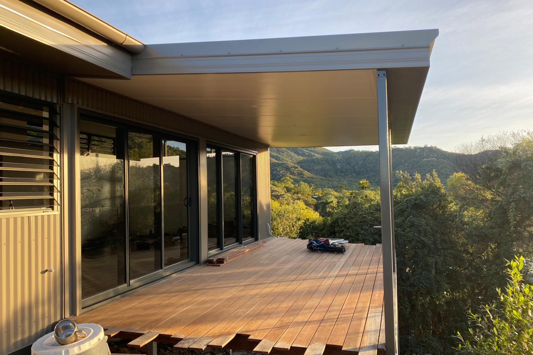Bush Retreat — covered timber deck with sliding glass doors and sweeping bush valley and mountain views