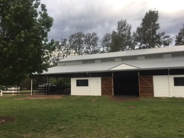 Stable — completed white stable building with timber doors and covered walkway