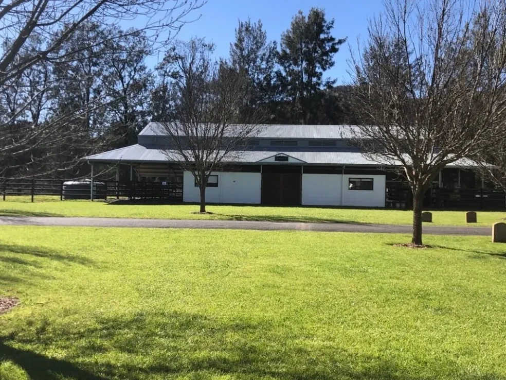 Stable — front facade with manicured lawn and surrounding trees