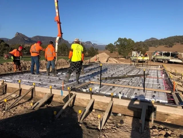 WIDDEN — workers laying reinforced concrete slab with mountain range behind