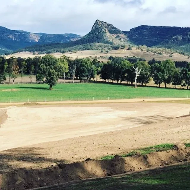 WIDDEN — site earthworks with graded pad and dramatic rocky peak in background
